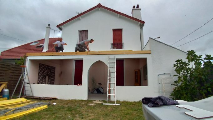 Maison à deux étages avec des travaux de construction en cours sur le toit.