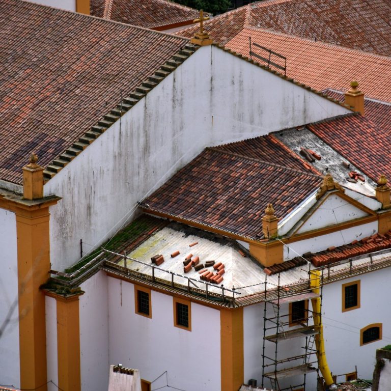 Toits d'un bâtiment avec des tuiles rouges et une structure en rénovation.