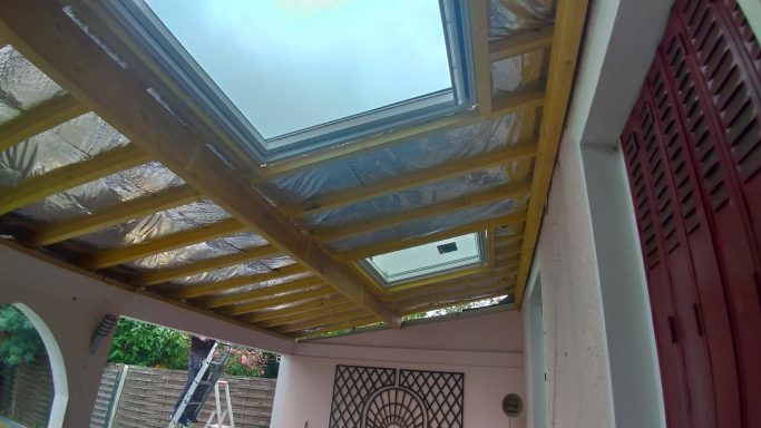 Plafond avec fenêtres de toit et structure en bois, vue vers le haut.