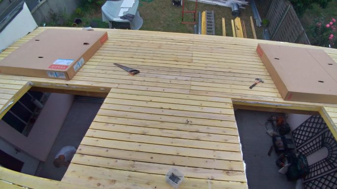 Vue d'une terrasse en bois avec des poutres et des outils sur le sol.